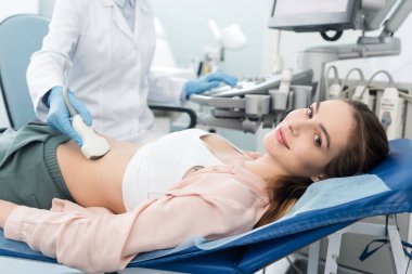 Doktor, klinikte ultrason taraması yapılan güzel bir hastanın midesini inceliyor. 
