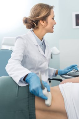 Profesyonel doktor, klinikte ultrason taraması yaptıran kadın hastanın böbreğini inceliyor.  