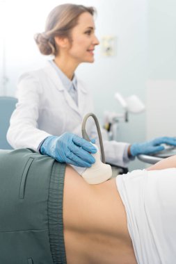 Profesyonel kadın doktor klinikte ultrason taraması yapılan hastanın böbreğini inceliyor.  