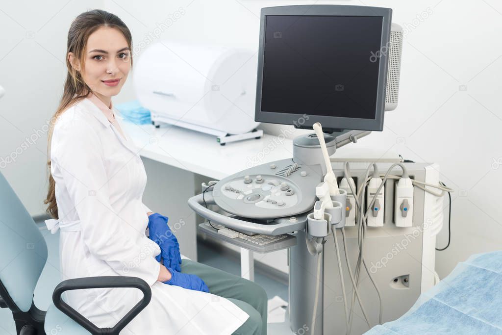 young happy doctor working with ultrasound scanner with blank screen in clinic