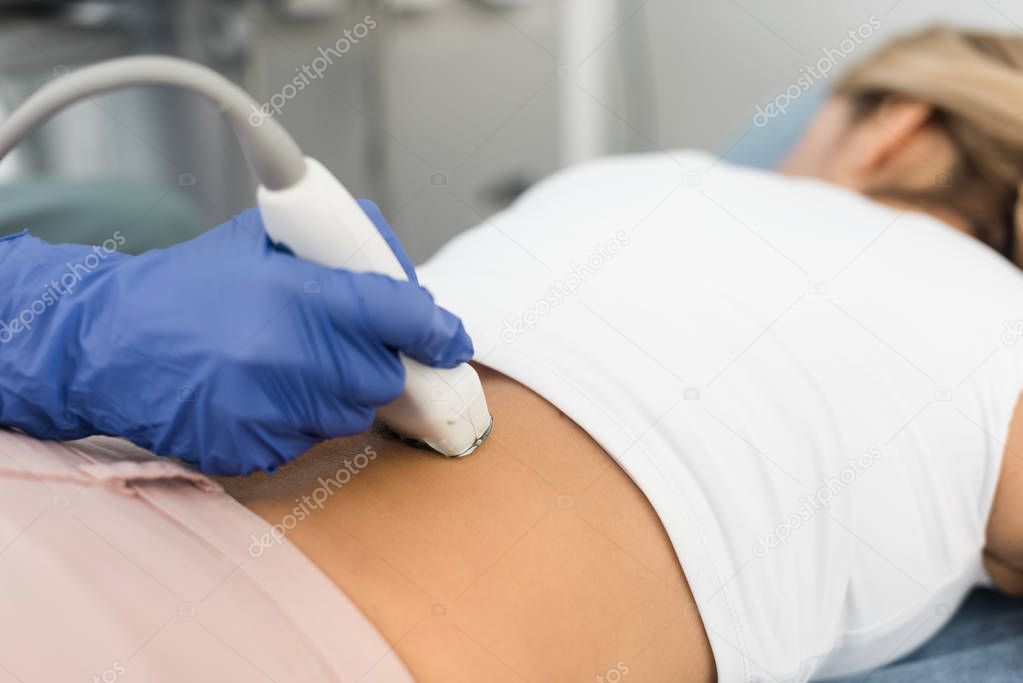 partial view of doctor examining kidney of female patient with ultrasound scan