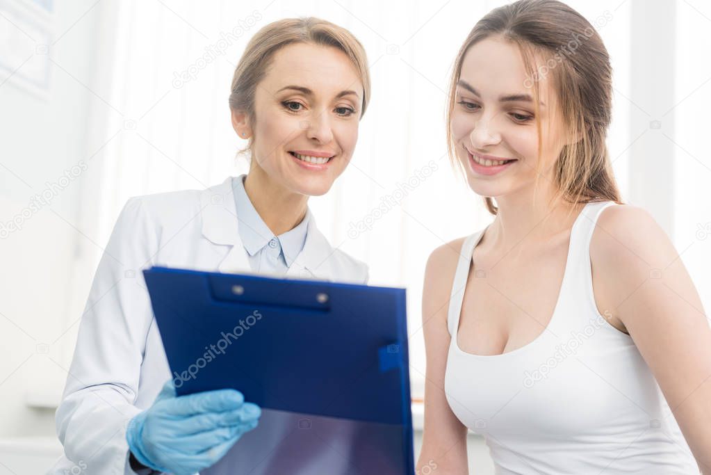 smiling doctor showing diagnosis to female patient in clinic
