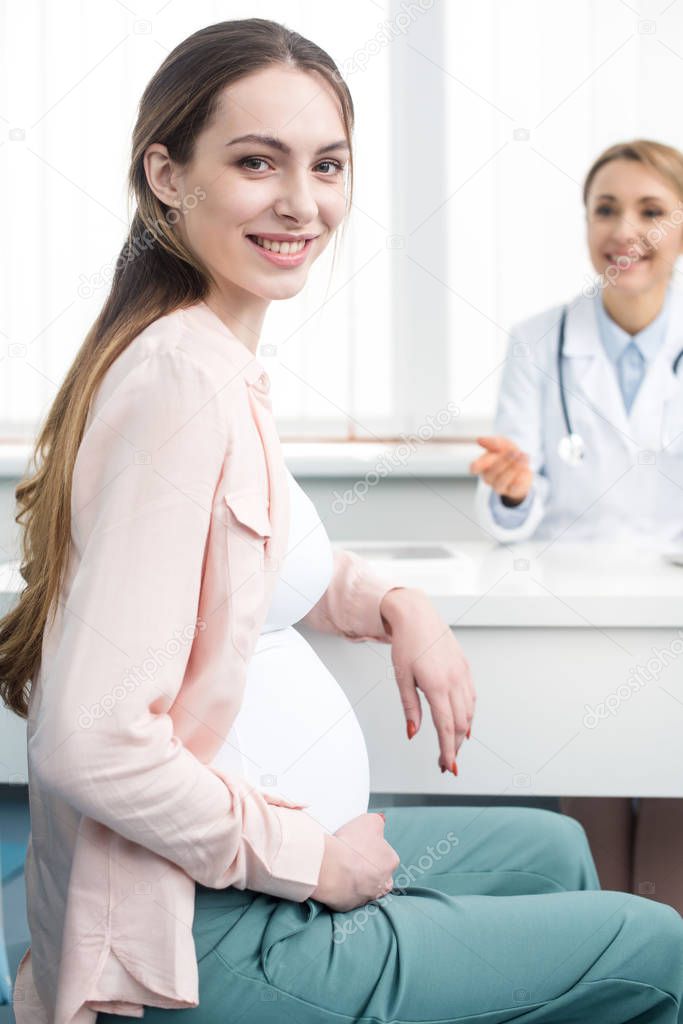 happy pregnant woman having consultation with gynecologist in clinic
