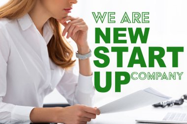 Cropped view of businesswoman with hand near chin holding dossier at table, we are new startup company illustration clipart