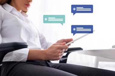 Masada otururken dijital tablet kullanan iş kadınının düşük açılı görüntüsü, konuşma baloncukları illüstrasyon