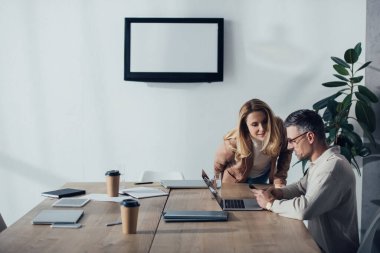 Gülümseyen meslektaşlar yaratıcı ajansta akıllı telefona bakıyorlar. 