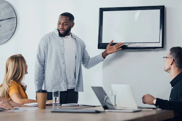 Sonriente Hombre Negocios Afroamericano Apuntando Con Mano Televisión Hablando Con — Foto de Stock