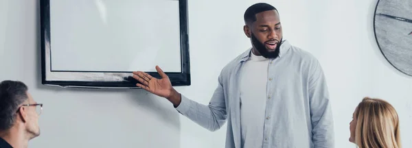 Plano Panorámico Sonriente Hombre Negocios Afroamericano Apuntando Con Mano Televisión — Foto de Stock