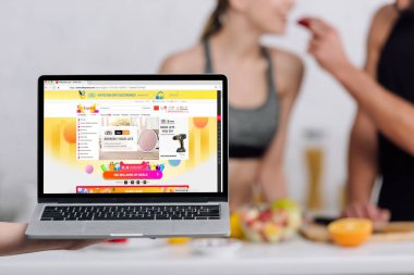 Kyiv, Ukrayna - 28 Aralık 2019: seçici dizüstü bilgisayar odaklı ve mutfaktaki çiftin yanında aliexpress web sitesi 