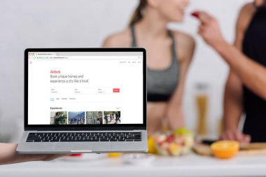Kyiv, Ukrayna - 28 Aralık 2019: laptopun seçici odak noktası ve mutfaktaki çift yanında havaalanı web sitesi 