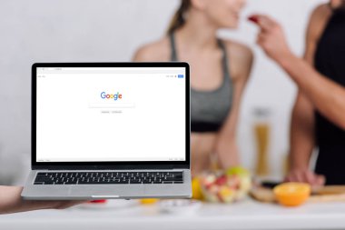 Kyiv, Ukrayna - 28 Aralık 2019: laptopun seçici odak noktası ve Google web sitesi mutfaktaki çifte yakın 