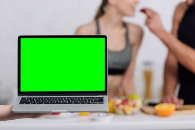 Mutfaktaki çiftin yanında yeşil ekranlı dizüstü bilgisayarın seçici odağı 