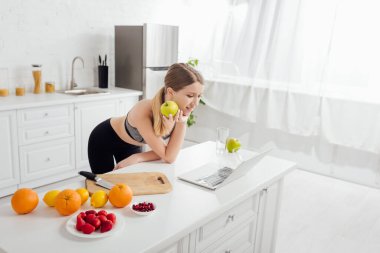 Lezzetli elmalı mutlu ve sportif kadın dizüstü bilgisayara bakıyor. 