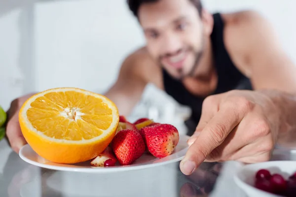 幸せな男の選択的な焦点は冷蔵庫から果物でプレートを取って — ストック写真