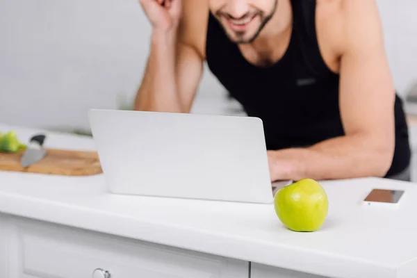 キッチンでアップルの近くでノートパソコンを使って幸せな男を切り取ると — ストック写真