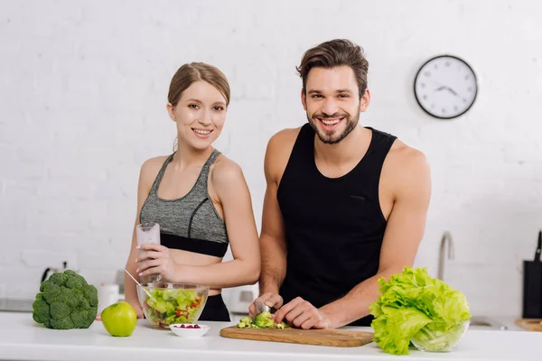 Mulher Feliz Segurando Vidro Smoothie Perto Homem Cozinhar Cozinha — Fotografia de Stock