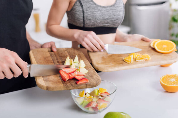 cropped view of man and woman cooking fruit salad 