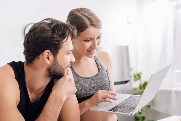 快乐的男人和女人在家里看笔记本电脑 — 图库照片