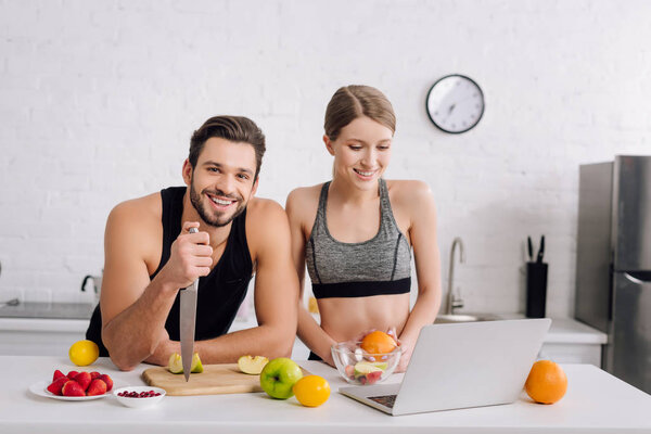 happy man with knife near fruits, woman and laptop 