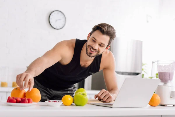 Glücklicher Mann Neben Laptop Mixer Mit Smoothie Und Leckeren Früchten — Stockfoto