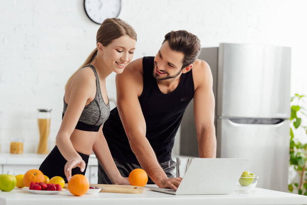 happy man and woman near laptop and tasty fruits 