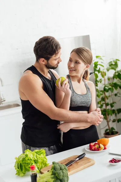 Hombre Feliz Abrazando Chica Ropa Deportiva Con Manzana —  Fotos de Stock