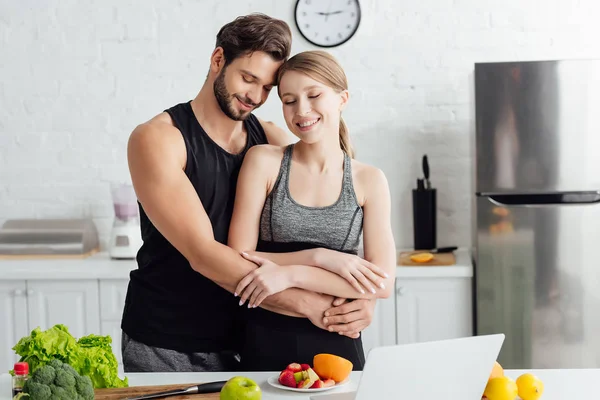 Hombre Feliz Abrazo Chica Ropa Deportiva Cerca Computadora Portátil Frutas — Foto de Stock