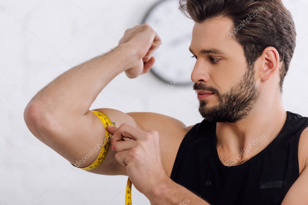 handsome and sportive man measuring muscle on hand  