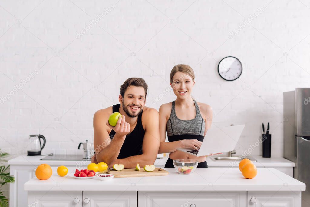 happy freelancers in sportswear near fruits and laptop 