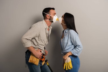 Mutlu el işçileri gri maske takıp öpüşüyor. 