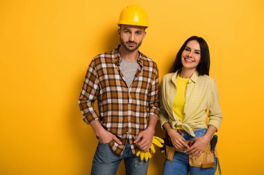 Profesyonel gülümseyen, sarı kemerli, miğferli el işçileri.     