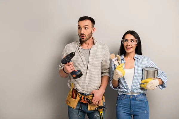 Excited Manual Workers Holding Paint Can Brushes Electric Drill Grey — Stock Photo, Image