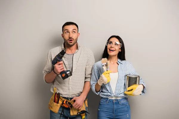 Excited Workers Holding Paint Can Brushes Electric Drill Grey — Stock Photo, Image