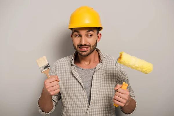 Pensoso Operaio Manuale Hardhat Guardando Rullo Vernice Pennello Sul Grigio — Foto Stock