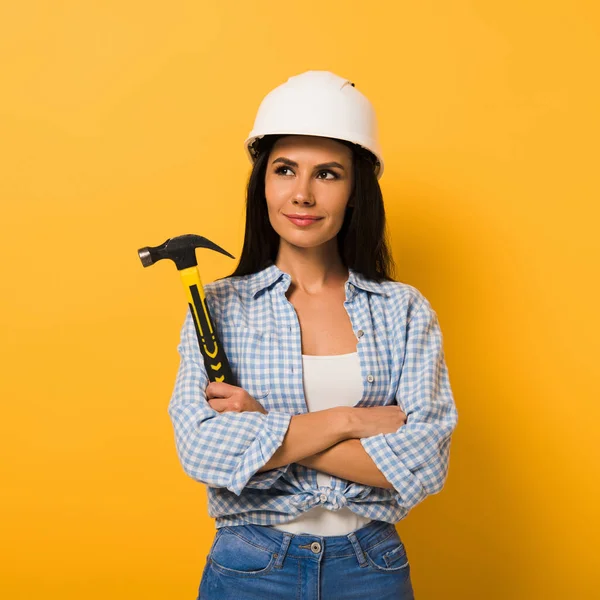 黄色で腕を組んでハンマーを持っている陽気な労働者の女性 — ストック写真