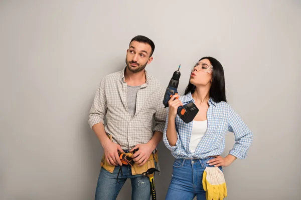 Skeptical Repairman Confident Female Worker Holding Electric Drill Grey — Stock Photo, Image