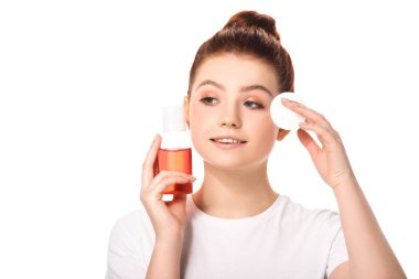 Temiz tenli güzel bir genç kız elinde pamuk sünger ve kırmızı makyaj temizleyicisi olan bir şişe, beyaz tenli.