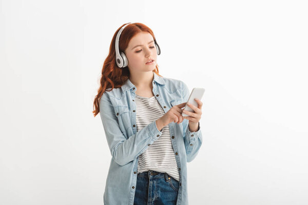 beautiful teen girl listening music with headphones and using smartphone, isolated on white