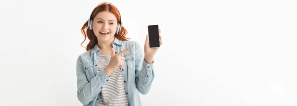 Panoramatický Záběr Šťastný Teenager Poslech Hudby Sluchátky Ukazuje Smartphone Prázdnou — Stock fotografie