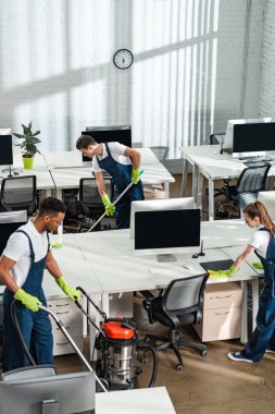 Modern açık uzay ofisinde çalışan çok kültürlü temizlik ekibi.