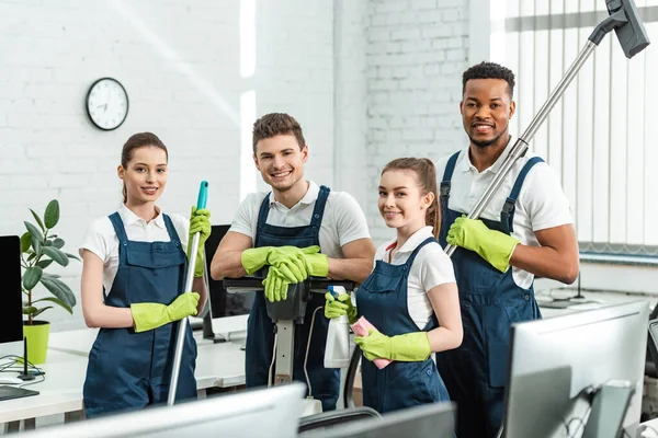 Happy Multicultural Cleaners Looking Camera While Standing Cleaning Supplies Office — Stock Photo, Image