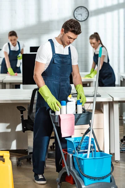 Junge Putzfrau Steht Neben Einkaufswagen Mit Putzutensilien — Stockfoto