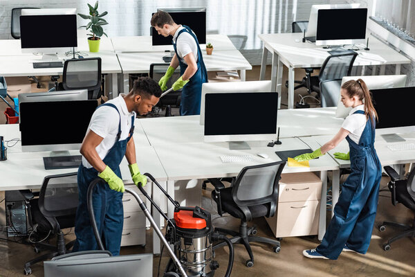 team of young multicultural cleaners working in modern open space office