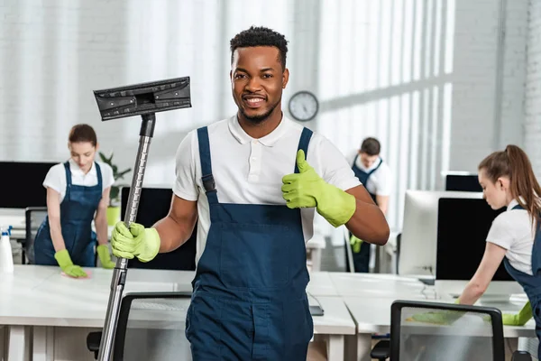 Tersenyum African American Cleaner Memegang Sikat Vacuum Cleaner Dan Menunjukkan — Stok Foto