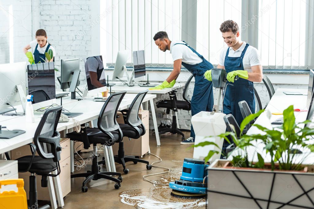 multicultural team of cleaners working in modern open space office