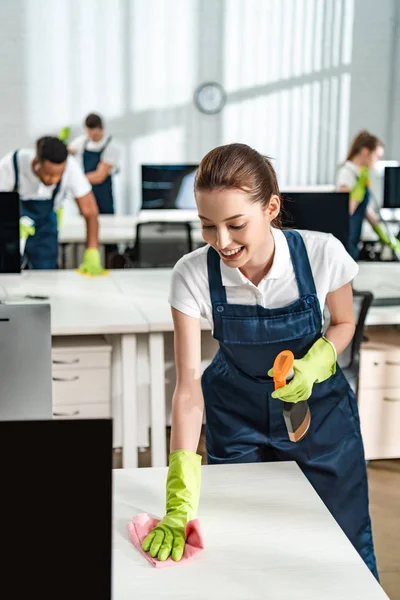 Fröhliche Putzfrau Overalls Putzt Büroschreibtisch Mit Lappen — Stockfoto