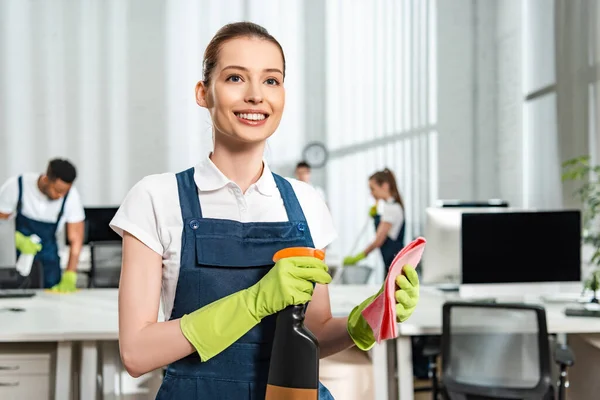 Attractive Cheerful Cleaner Holding Spray Bottle Rag While Looking Away — Stock Photo, Image