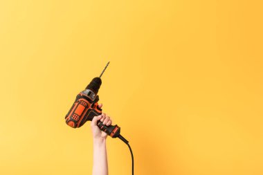 cropped view of woman holding drill on yellow background  clipart