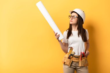 Sarı arka plan planına bakıp, elinden her iş gelen düşünceli bir kadın. 