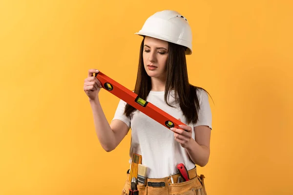 Concentrated Handywoman Holding Spirit Level Yellow Background — Stock Photo, Image
